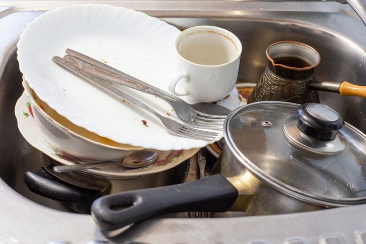 dirty dishes after dinner lie in the sink, cleaning the table in the kitchen