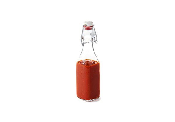 a single bottle of ketchup with wire bail lid on a pure white background